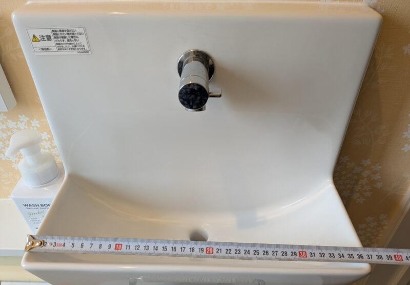 2階トイレの手洗い器の幅をメジャーで測っている