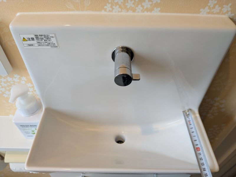 2階トイレの手洗い器の奥行をメジャーで測っている
