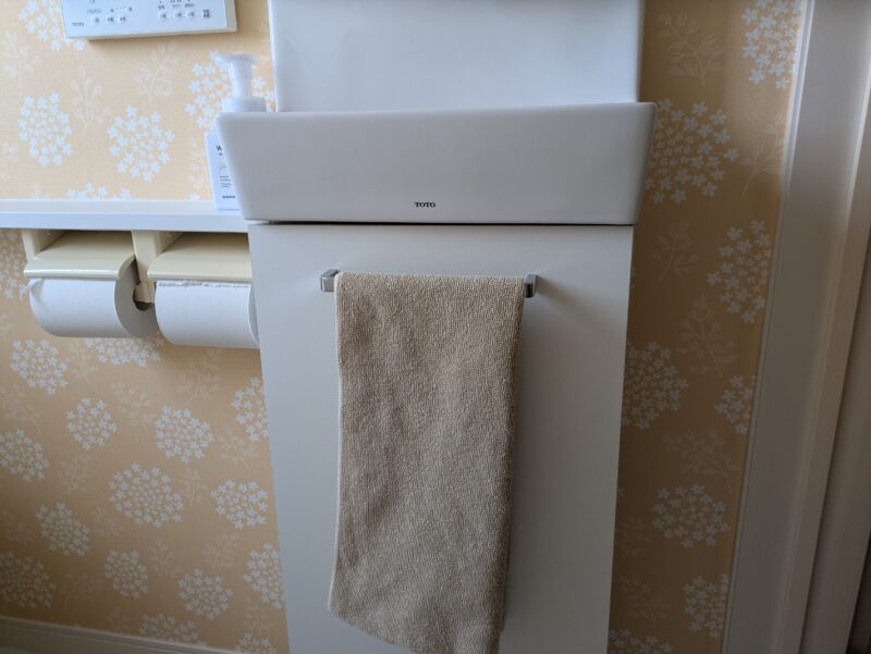 2階トイレの手洗い器と、収納の扉に掛けたタオル。横にペーパーホルダーがある