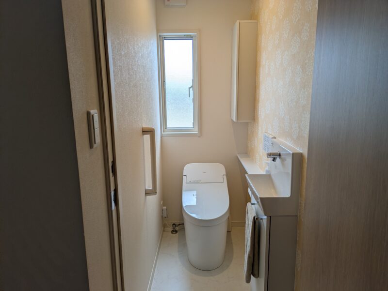 2階トイレの全景。便器、独立した手洗い器、窓が見える